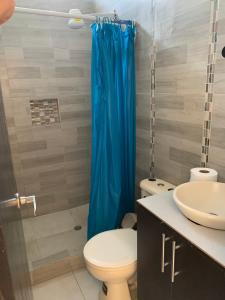 a bathroom with a toilet and a blue shower curtain at Brisa Blanca in Punta Blanca