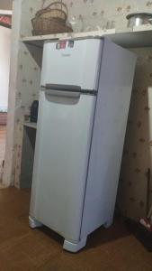 a white refrigerator sitting in a kitchen next to a shelf at Casa de Praia - Alcobaça-BA - em frente ao Condomínio Gaivotas in Alcobaça