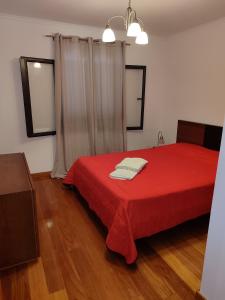 a bedroom with a red bed with two towels on it at Delfina`s House in Machico