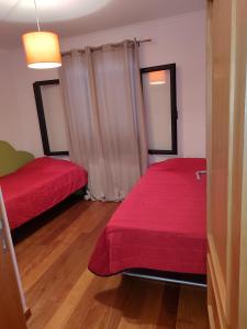 een kamer met 2 bedden met rode lakens en houten vloeren bij Delfina`s House in Machico