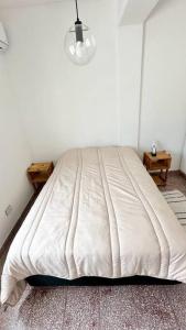 a white bed in a room with two tables at Temporarios Calle Formosa in Resistencia