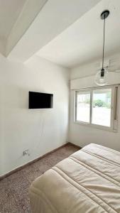 a white bedroom with a bed and a window at Temporarios Calle Formosa in Resistencia