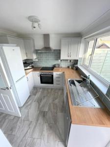 a kitchen with white cabinets and a large window at Peaceful centrally located, 2 Bedroom Bungalow. in Camborne