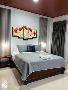 1 dormitorio con 1 cama con 3 cuadros en la pared en Hotel la casona de Wiky, en Guaduas