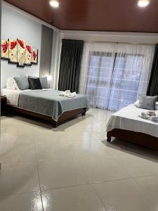 um quarto com 2 camas e uma grande janela em Hotel la casona de Wiky em Guaduas