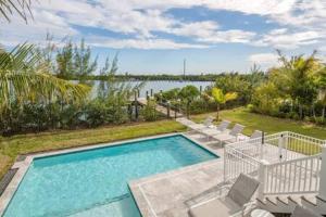 a swimming pool with lounge chairs at Springtide House -Dock & Home w Pool in Stock Island