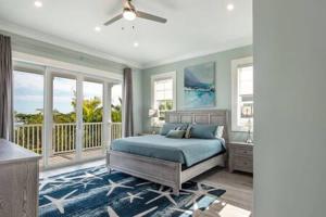 a bedroom with a blue bed and a balcony at Springtide House -Dock & Home w Pool in Stock Island