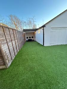 a backyard with a fence and green grass at Hertford HOME in Hertford