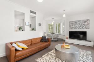 a living room with a brown couch and a table at Boutique Stays - Wellington Mews in Melbourne