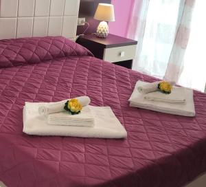 a purple bed with towels and flowers on it at B&B La Perla in Racale