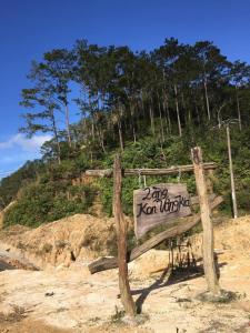 a wooden sign sitting on the sand near a hill at Y Bé Homestay, Kon Vơng Kia, Măng Đen 