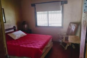 a bedroom with a red bed and a window at Cabaña La tortuga in Siguatepeque