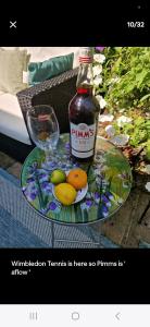 a bottle of gin sitting on a glass table with fruit at Homestay, Upmarket, Wimbledon & Southfields; beside tube; (20 mins to centre) walk to Tennis : in London