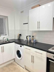 a kitchen with white cabinets and a washing machine at Luxury SuperKingsize Bed in London in London