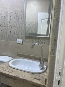 a bathroom with a sink with a mirror and a toilet at Monte cairo Pool View in Cairo +8 photos