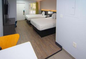 Habitación de hotel con 2 camas y escritorio en Studio 6-Coral Springs, FL - Fort Lauderdale, en Coral Springs