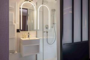 a bathroom with a sink and a shower with a mirror at Best Western Plus Bretagne Montparnasse in Paris