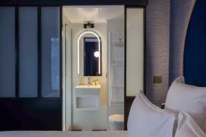 パリにあるベストウエスタン ブルターニュ モンパルナスのベッドルーム1室(洗面台、鏡付きのバスルーム付)