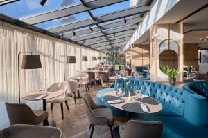 a restaurant with a blue couch and tables and chairs at Hotel Imperial Plovdiv, a member of Radisson Individuals in Plovdiv