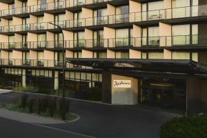 un edificio de apartamentos con una señal de aania delante de él en Radisson Resort Kołobrzeg en Kołobrzeg