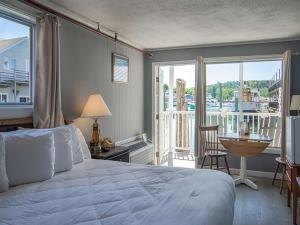 a bedroom with a bed and a balcony with a view at Fisherman's Wharf Inn in Boothbay Harbor