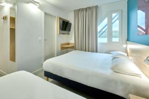 ナルボンヌにあるKyriad Direct Narbonne Sudのベッド2台と窓が備わるホテルルームです。