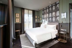 a bedroom with a white bed and a large window at Radisson Collection Hotel, Roma Antica in Rome
