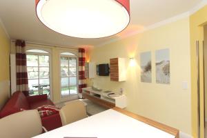 a living room with a red couch and a large light fixture at strandnah, Ferienwohnung mit Sauna- und Schwimmbadnutzung - Strandresidenz Baabe FeWo1-29 in Baabe