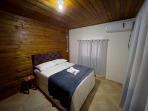 een slaapkamer met een bed met een houten muur bij Casa Jardinada in Pomerode