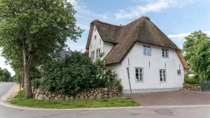 a small white house with a thatched roof at Altes Schulmeisterhaus Wohnung 1 in Oevenum
