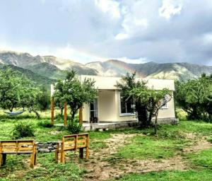 una casa en un campo con montañas en el fondo en Casa de montaña en Cortaderas