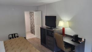 a room with a desk with a television and a table with a lamp at Quality Inn Forsyth near GA Public Safety Training Center in Forsyth +21 photos