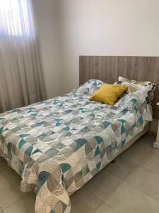 a bed with a comforter and a yellow pillow on it at Acogedor apartamento en Canning in Canning