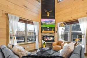 sala de estar con sofá y TV en SmokiesBoutiqueCabins would love to host you at our NEW cabin! 3 King Suites, Indoor Pool, Game Room, Lounge with 75" TV! Close to Dollywood and the Parkway! en Pigeon Forge