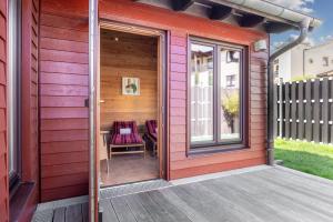 eine offene Tür eines roten Hauses mit einer Terrasse in der Unterkunft Urlaubsräume am Meer Urlaubsräume am Meer 3-15 in Fulgen