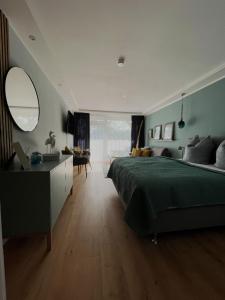 ein Schlafzimmer mit einem großen grünen Bett und einem Spiegel in der Unterkunft Haus Vier Jahreszeiten am See Vier Jahreszeiten - HS 221 in Goslar