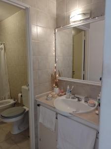 y baño con lavabo, aseo y espejo. en Departamento Alvear 388 en Salta