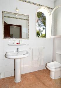a white bathroom with a sink and a toilet at Hostal La Ceiba in Cala d´Or