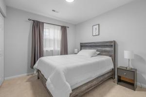 een witte slaapkamer met een groot bed en een raam bij Enormous 6 BR Family Style Home By Waterside in Hampton