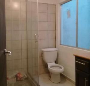 ein Bad mit einem weißen WC und einem Fenster in der Unterkunft Suite equipada 2 camas mat, sala y cocina junto a Tec Santa Fe in Mexiko-Stadt