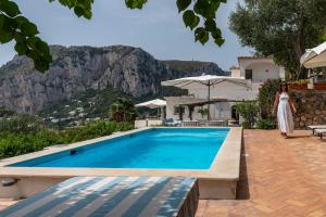 una mujer con un vestido blanco parada junto a una piscina en Beautiful Villa with View in the heart of Capri, en Capri