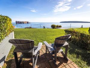 two chairs sitting on a patio looking out at the ocean at Hôtel le Mirage in Perce