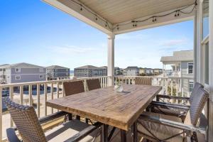 a deck with a wooden table and chairs on a balcony at Beers and Sunshine Ocean Isle Beach, Heated pool, elevator, across from beach access in Ocean Isle Beach