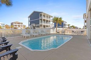 a swimming pool with chairs and a building at Beers and Sunshine Ocean Isle Beach, Heated pool, elevator, across from beach access in Ocean Isle Beach