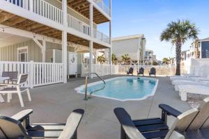 a patio with a swimming pool and chairs at Beers and Sunshine Ocean Isle Beach, Heated pool, elevator, across from beach access in Ocean Isle Beach