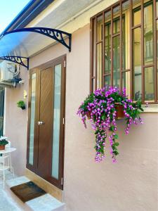 een deur van een huis met een hangende mand met paarse bloemen bij Lætitia Cottage Apartment in Aversa