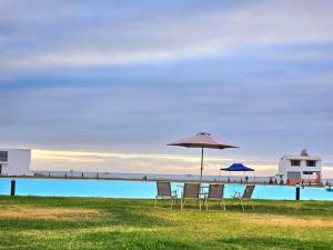 grupa krzeseł i parasol obok basenu w obiekcie Casa de Playa Luxury Laguna Azul Tacna w mieście Tacna