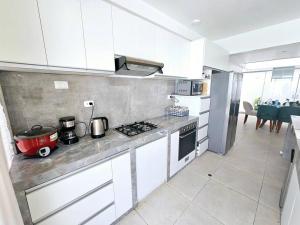 uma cozinha com armários brancos e um forno com placa de fogão em Casa de Playa Luxury Laguna Azul Tacna em Tacna
