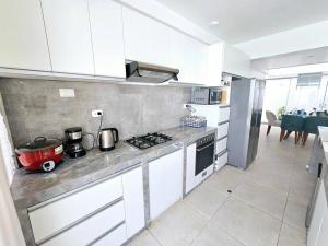 cocina con armarios blancos y fogones en Casa de Playa Luxury Laguna Azul Tacna, en Tacna