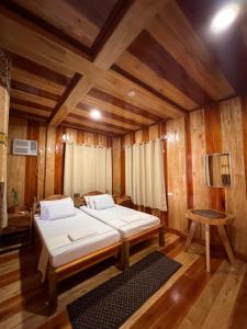 two beds in a room with wooden walls and wooden floors at Ozar Homestay in Mambajao